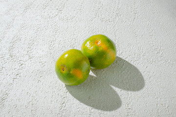 Green orange gradient citrus fruit isolated on a textured white background, showcasing its vibrant color transition