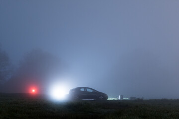 A car parked by a field on a foggy night