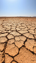 Cracked Dry Earth Texture Background Under Bright Sun: Depicts Drought, Climate Change, Desertification, and Water Scarcity Issues
