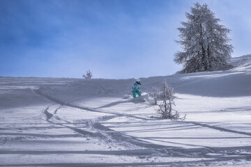 A snowboarder skillfully glides down an untouched snowy slope under a clear blue sky, surrounded by...