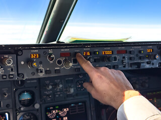 Pilot setting or adjusting autopilot in passenger airplane in flight