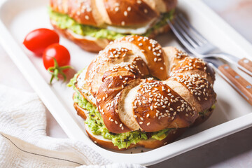 Breakfast bagel with egg and avocado guacamole on a white plate.
