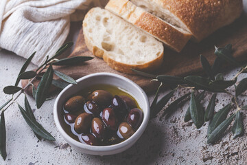 Natural kalamata olives in oil with spices and fresh ciabatta. Mediterranean food concept.