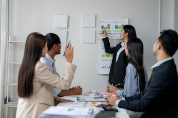A group of people are sitting around a table with a woman giving a presentation