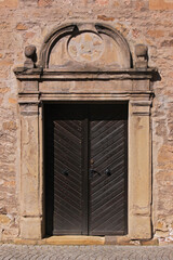 Brown wooden door in a baroque sandstone portal with a broken pediment on the facade of Philippskirche church in the old town of Bad Sobernheim, Germany
