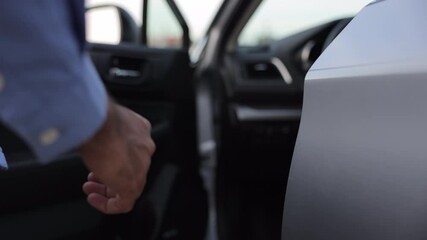 Anonymous man driver in casual wear, holding door handle, getting into car outdoors. Close up of male hand with wrist watch opening car door, ready to go. Concept of travel, car rental, business.