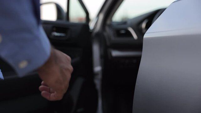 Anonymous man driver in casual wear, holding door handle, getting into car outdoors. Close up of male hand with wrist watch opening car door, ready to go. Concept of travel, car rental, business.
