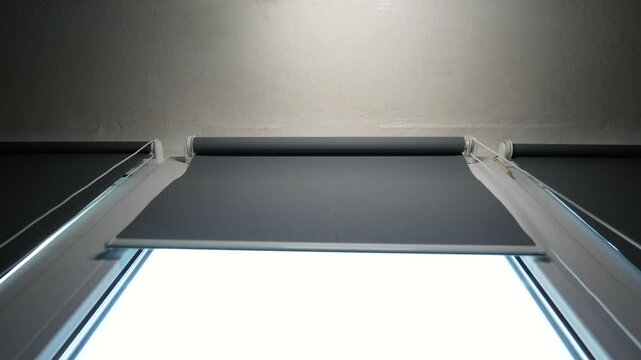 Opening blinds on the window. Low angle. fabric roller blinds. Concept of waking up in the morning.