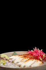 Eel sashimi with lime and ice on a bamboo leaf on a black background