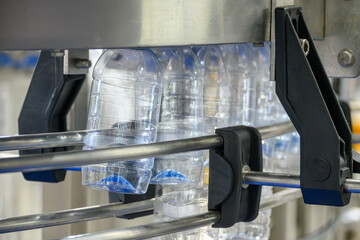 The  empty drinking water bottles  hanging on the conveyor belt for filling process.