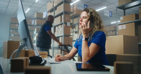 Warehouse facility of post office or E-commerce store: Female logistics coordinator talks by mobile...