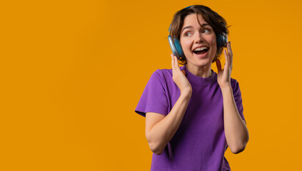 Joyful woman listening music in vibrant yellow studio, headphones on, fully immersed in. Her energy and happiness fill room as she moves with confidence and rhythm.