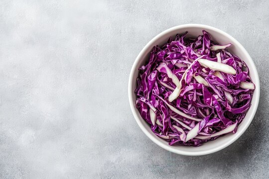 Close up of red cabbage salad in a white bowl on a light stone surface emphasizing vegetarian and healthy eating