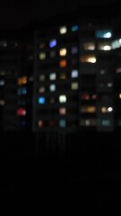 Fototapeta premium The lights are on in the windows of the houses at night, blurred.