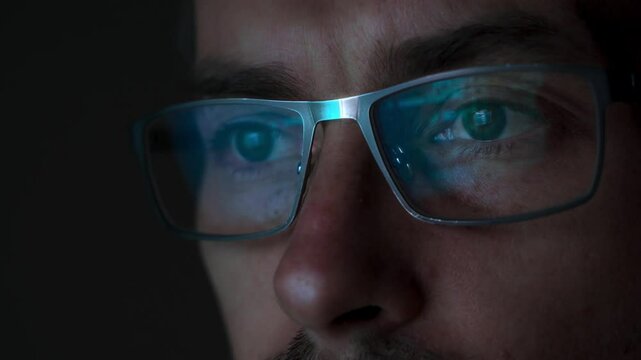 Close-up of a programmer face wearing eyeglasses, with programming code reflected on the lenses. Software engineer or AII developer at work. Copy space