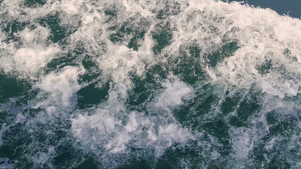 ship's wake in emerald green water. white water spray in sunlight. wild speed trail pattern