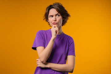 Thinking around stylish woman on yellow background. Puzzled lady looking answer