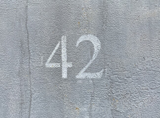 White number 42 on gray background. Forty two on textured surface 