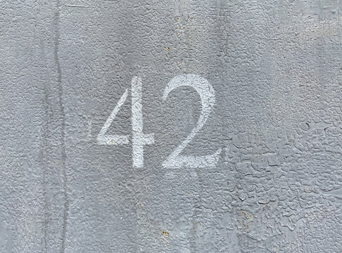 White number 42 on gray background. Forty two on textured surface 