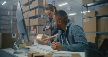 African American logistics coordinator works on computer in post office. Female warehouse associate...