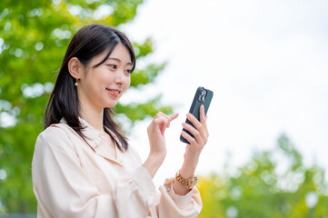 公園でスマホ操作をする日本人女性