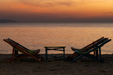 Silhouette of a chair at sunrise on a beautiful beach in Thailand.