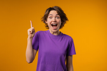 Breakthrough genius idea. Happy woman having eureka moment, pointing finger up on yellow...