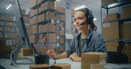 Warehouse of postal service or E-commerce store: Female logistics coordinator talks by headset with...