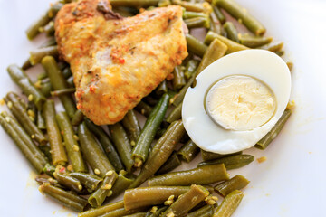 A plate of food with a chicken, beans, and an egg