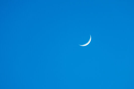 A crescent moon is flying through a clear blue sky