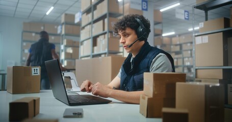 Customer support specialist in logistics wearing headset talks to customer on call, uses laptop...
