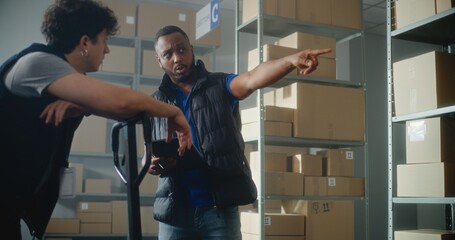 Multiethnic warehouse employees working in sorting center of delivery service or online store:...