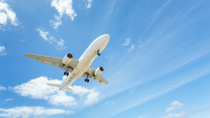 Low angle view of an aeroplane flying in a partly cloudy blue sky