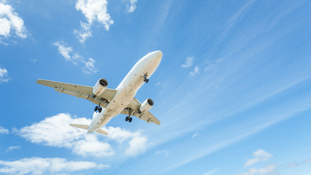 Low angle view of an aeroplane flying in a partly cloudy blue sky