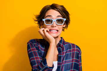 Fototapeta premium Portrait of frightened girl wear checkered shirt in 3d glasses watch horror movie biting fingers isolated on yellow color background