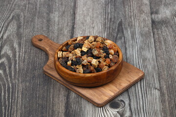 Mix of nuts and dried fruits in wooden bowl isolated on a wooden background.