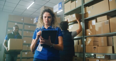 Female logistics specialist uses tablet computer and stylus, checks inventory. Warehouse...