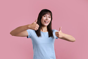 Happy woman showing thumbs up on pink background. Like gesture