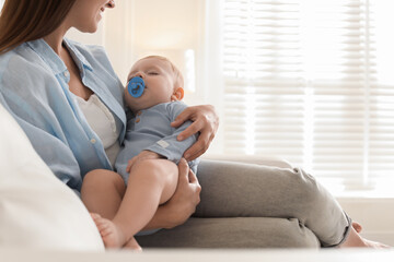 Mother with her sleeping baby on sofa indoors, closeup. Space for text