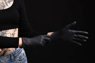 Professional tattoo artist wearing gloves on black background, closeup