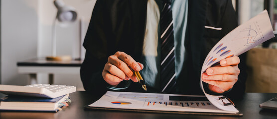 Accountant working at desk using calculator to calculate company's annual financial and tax report....