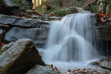 Obraz premium A small waterfall between stones in autumn. 