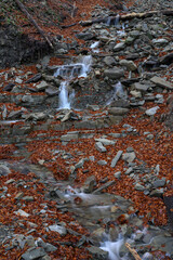 A small waterfall between stones in autumn.
