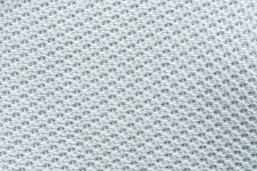 Detailed close-up texture of soft light gray knitted fabric with intricate patterns
