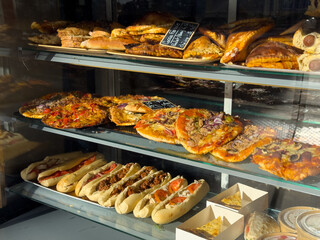Wide variety of baked goods displayed in a bakery window during a sunny day