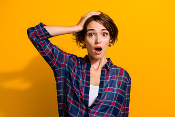 Portrait of speechless lovely girl with bob hairstyle wear checkered shirt hold arm on head staring...
