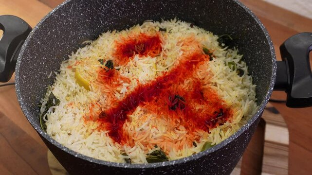 Mixing biryani, spicy coloured rice with beaf