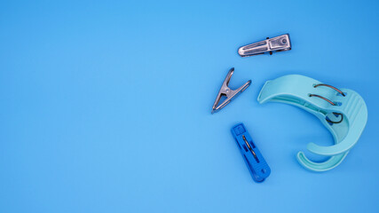Clothespins placed on a blue background. Top view plastic and stainless clothespins with copy space with concept of clothing, household items for clothes, textiles, and housework.