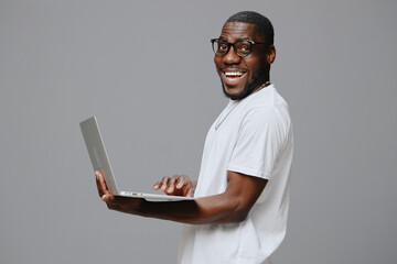 young man, technology, laptop, casual wear, joy, smiling, grey background, happiness, lifestyle, digital, modern, professional, confident, work, communication, creative, productivity, African descent