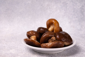 pickled milk mushrooms lie on a white plate, on a white background, space for copy